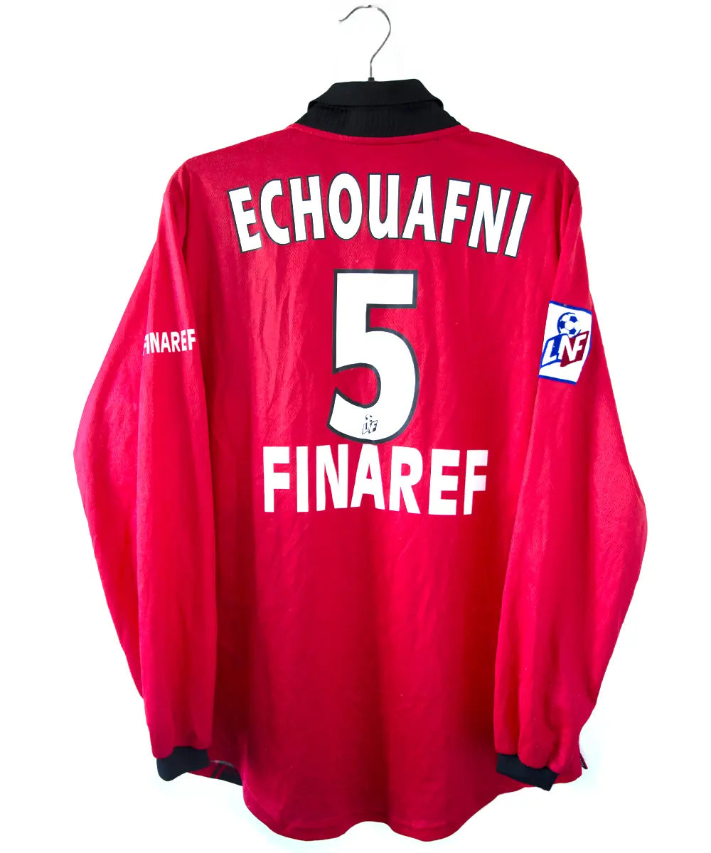 Maillot domicile du stade rennais porté lors de la saison 2000-2001 par Echouafni. Le maillot est de couleur rouge et noir. On peut retrouver l'équipementier asics et les sponsor Pinault et Finaref.