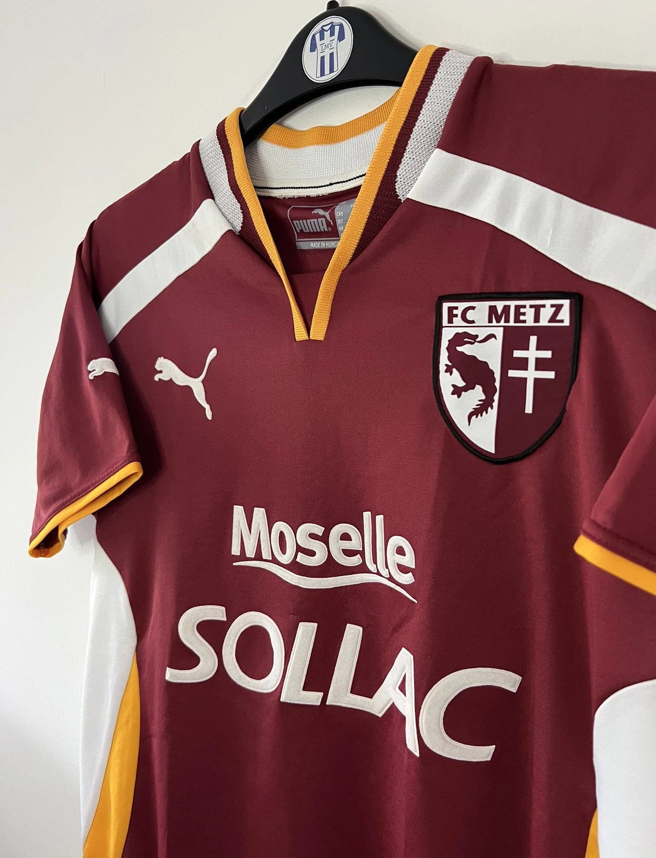 Maillot de foot vintage domicile rouge blanc et jaune du FC Metz de la saison 2001/2002. On peut retrouver l'équipementier Puma et le sponsor Sollac. Il s'agit d'un maillot authentique d'époque.