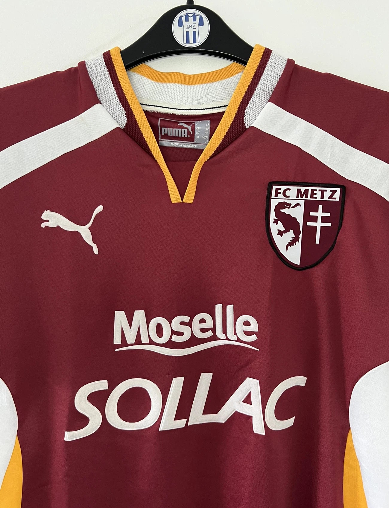 Maillot de foot vintage domicile rouge blanc et jaune du FC Metz de la saison 2001/2002. On peut retrouver l'équipementier Puma et le sponsor Sollac. Il s'agit d'un maillot authentique d'époque.
