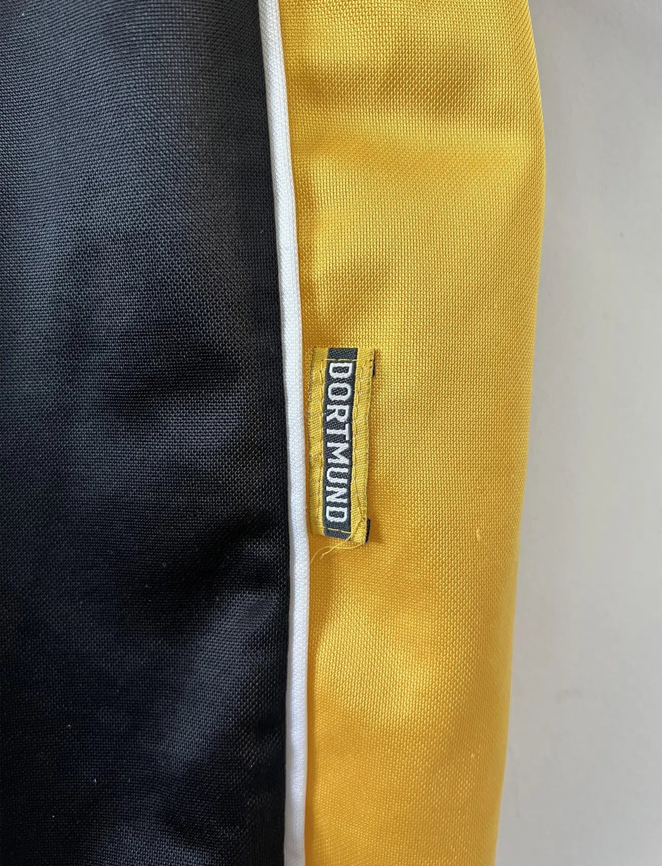 Maillot de foot vintage du Borussia Dortmund de la saison 1998/2000. Le maillot est de couleur noir et jaune. On peut retrouver l'équipementier nike et le sponsor s.Oliver. Le maillot possède l'étiquette d'authenticité F8-PKH. Il s'agit d'un maillot authentique d'époque.