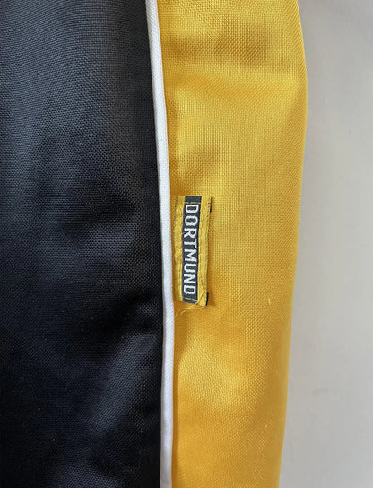 Maillot de foot vintage du Borussia Dortmund de la saison 1998/2000. Le maillot est de couleur noir et jaune. On peut retrouver l'équipementier nike et le sponsor s.Oliver. Le maillot possède l'étiquette d'authenticité F8-PKH. Il s'agit d'un maillot authentique d'époque.