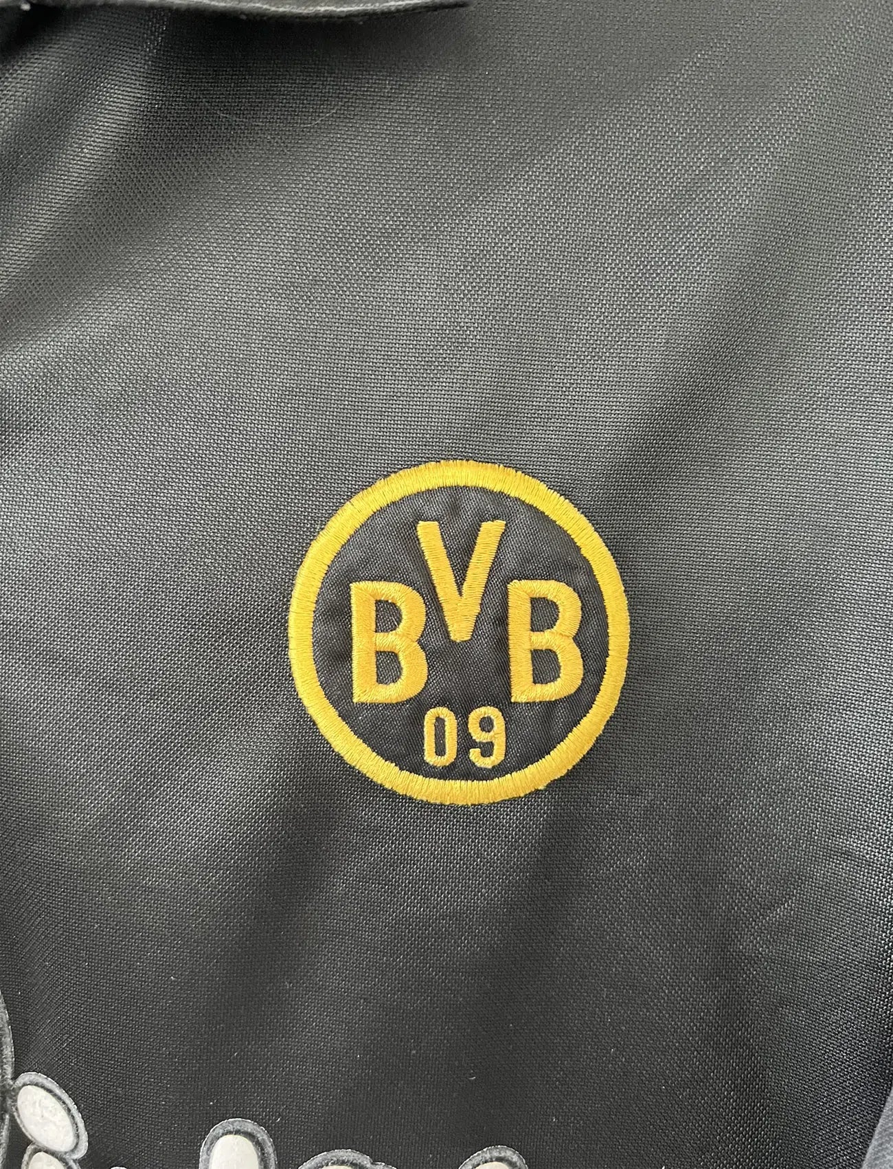 Maillot de foot vintage du Borussia Dortmund de la saison 1998/2000. Le maillot est de couleur noir et jaune. On peut retrouver l'équipementier nike et le sponsor s.Oliver. Le maillot possède l'étiquette d'authenticité F8-PKH. Il s'agit d'un maillot authentique d'époque.