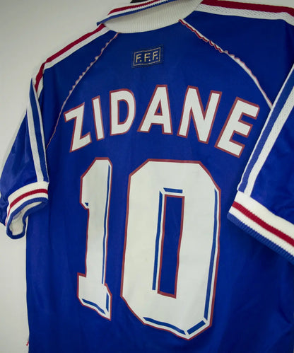 Maillot vintage bleu blanc rouge de l'équipe de france 1998. On peut retrouver l'équipementier adidas. Le maillot est floqué du numéro 10 Zinedine Zidane