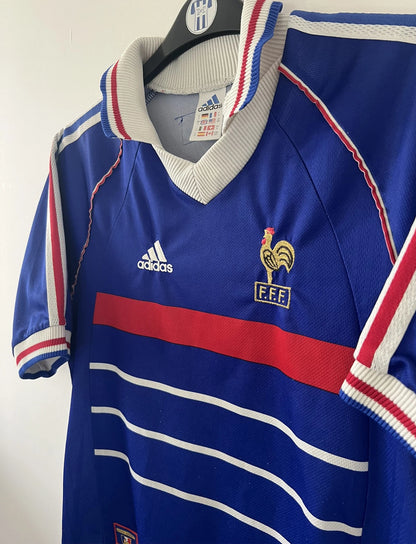 Maillot de foot vintage domicile bleu de l'Equipe de France 1998. On peut retrouver l'équipementier adidas. Il s'agit d'un maillot authentique d'époque.