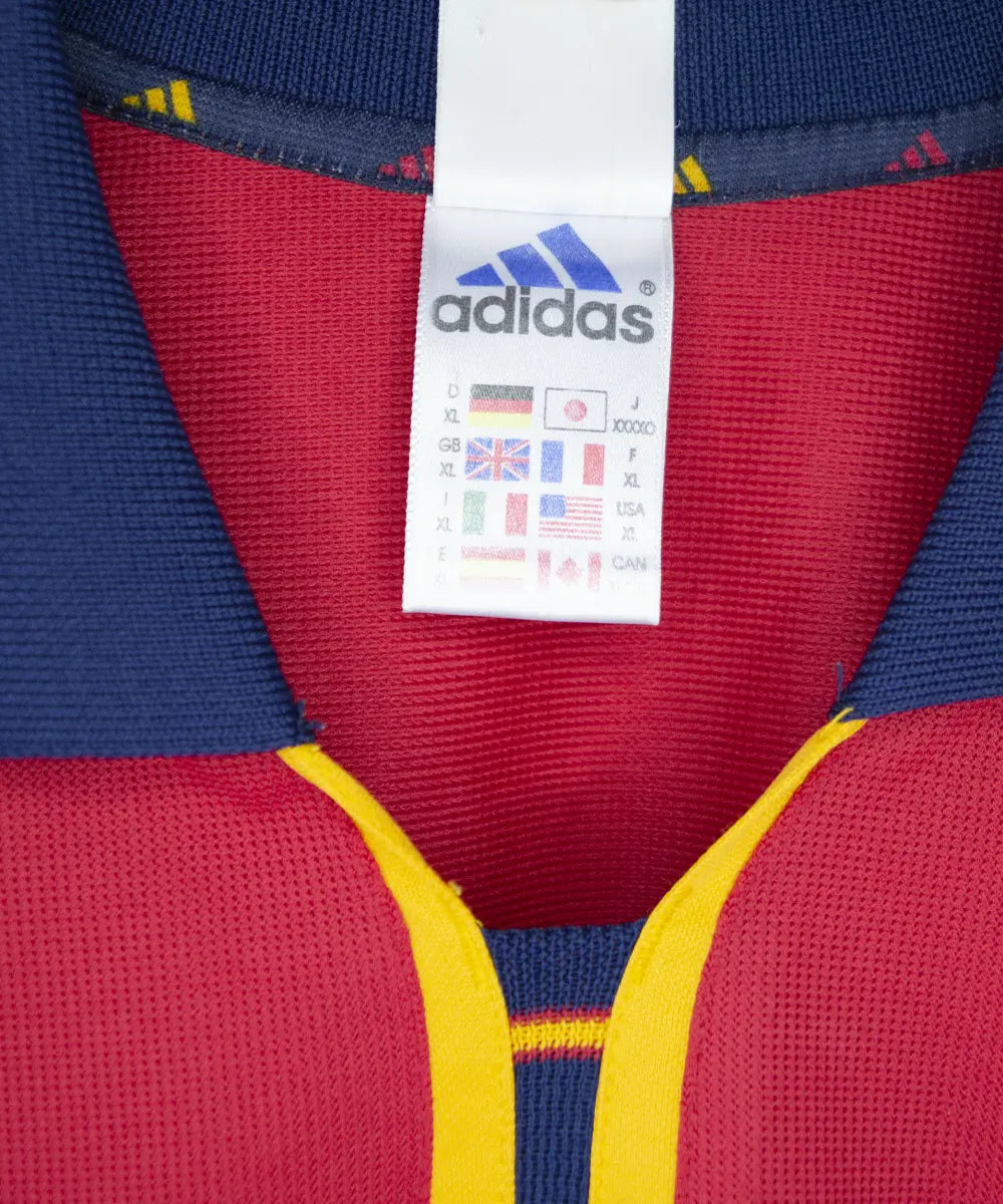 Maillot domicile de l'espagne de couleur rouge, bleu et jaune de 1999 à 2002. On peut retrouver l'équipementier adidas.