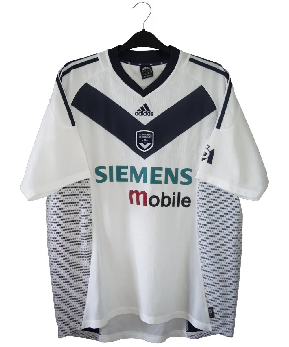 Maillot extérieur des girondins de bordeaux de couleur blanc et bleu. On peut retrouver l'équipementier adidas et le sponsor siemens mobile et M6. L'étiquette du maillot comporte les numéros AKU001