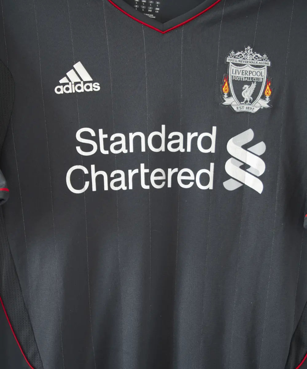 Maillot extérieur de liverpool de la saison 2011-2012. Le maillot est de couleur noir, gris et rouge. On peut retrouver l'équipementier adidas et le sponsor standard chartered.