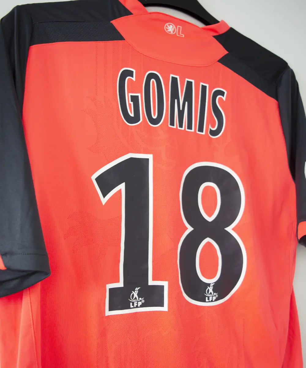 Maillot extérieur orange et noir de l'olympique lyonnais. On peut retrouver l'équipementier umbro et le sponsor apicil. Le maillot est floqué du numéro 18 Gomis