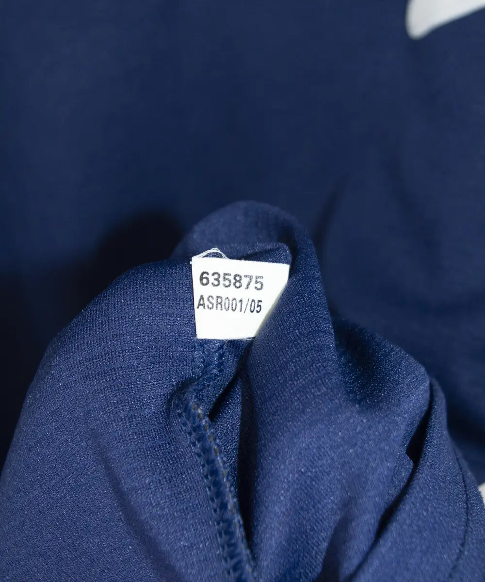 Maillot vintage extérieur bleu et blanc de l'om de la saison 1999-2000. On peut retrouver l'équipementier adidas et le sponsor ericsson. Sur cette photo on peut voir l'étiquette comportant les numéros 635875