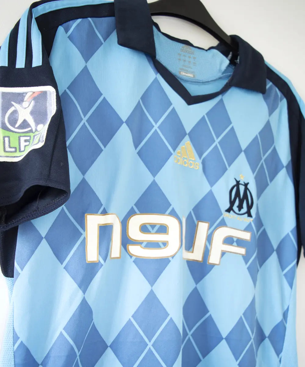 Maillot extérieur de côté bleu clair et bleu foncé de l'om de la saison 2008-2009. Le maillot est floqué du numéro 20 Ben Arfa. On peut retrouver sur le maillot, l'équipementier adidas, le sponsor neuf, le sponsor nasuba et le sponsor groupama