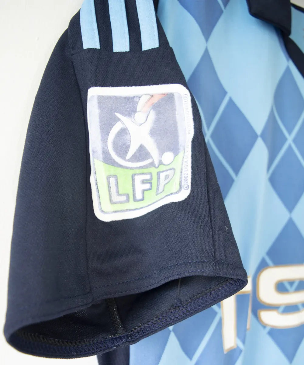 Maillot extérieur bleu clair et bleu foncé de l'om de la saison 2008-2009. Le maillot est floqué du numéro 20 Ben Arfa. On peut retrouver sur le maillot, l'équipementier adidas, le sponsor neuf, le sponsor nasuba et le sponsor groupama. Sur cette photo on peut voir le patch lfp