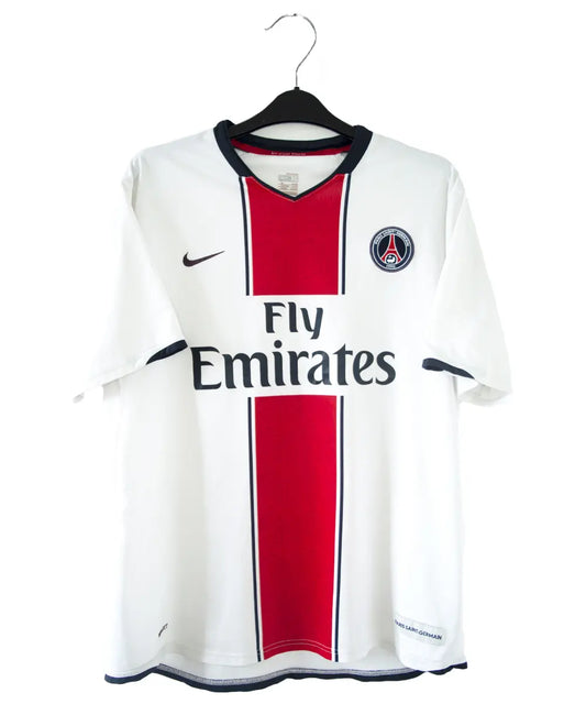 Maillot extérieur du psg de la saison 2007-2008. Le maillot est de couleur blanc, rouge et bleu. On peut retrouver l'équipementier nike et le sponsor fly emirates