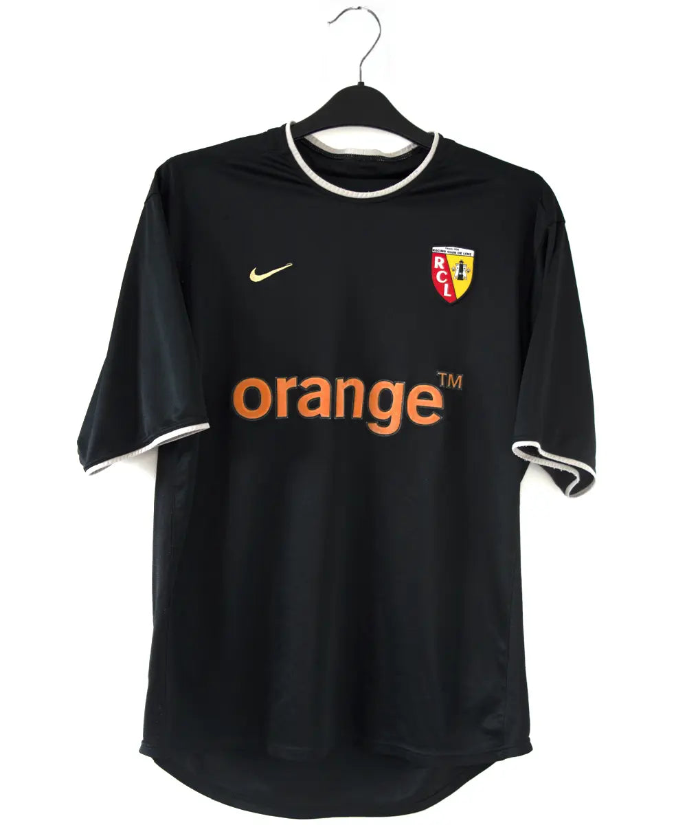 Maillot extérieur du RC Lens de la saison 2002-2003 de couleur noir et blanc. On peut retrouver l'équipementier nike et le sponsor orange.