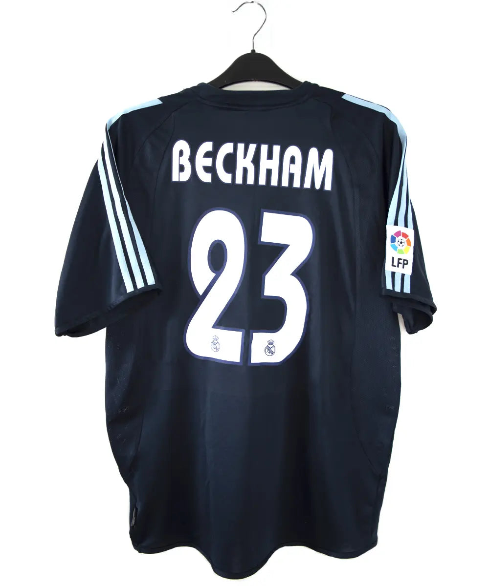 Maillot de foot vintage noir et bleu du real madrid de la saison 2003-2004. On peut retrouver l'équipementier adidas et le sponsor siemens mobile. Le maillot est floqué du numéro 23 Beckham. Il s'agit d'un maillot authentique.
