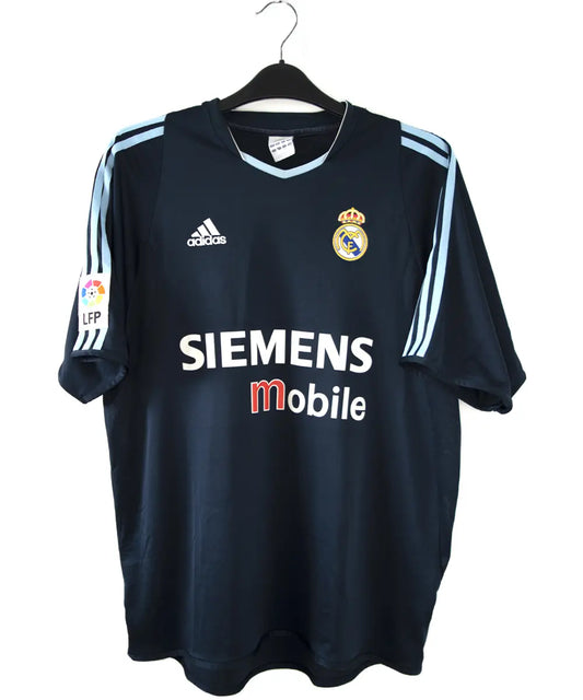 Maillot de foot vintage noir et bleu du real madrid de la saison 2003-2004. On peut retrouver l'équipementier adidas et le sponsor siemens mobile. Le maillot est floqué du numéro 23 Beckham. Il s'agit d'un maillot authentique.