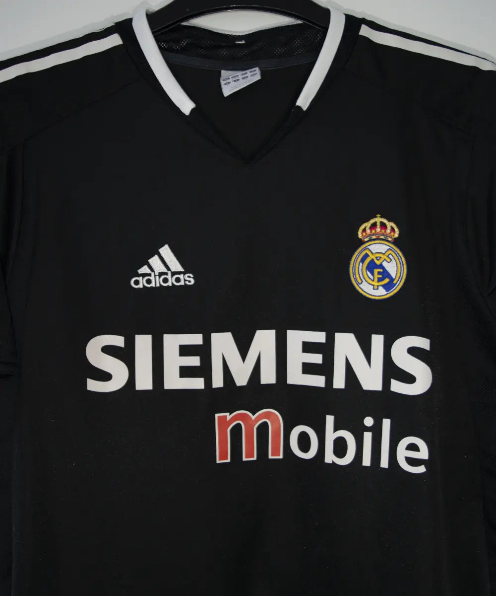 Maillot vintage extérieur noir et blanc du real madrid de la saison 2004-2005. On peut retrouver l'équipementier adidas et le sponsor siemens mobile. Le maillot est floqué du numéro 5 Zinedine Zidane