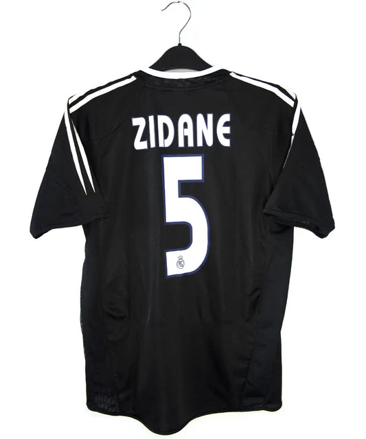 Maillot vintage extérieur noir et blanc du real madrid de la saison 2004-2005. On peut retrouver l'équipementier adidas et le sponsor siemens mobile. Le maillot est floqué du numéro 5 Zinedine Zidane