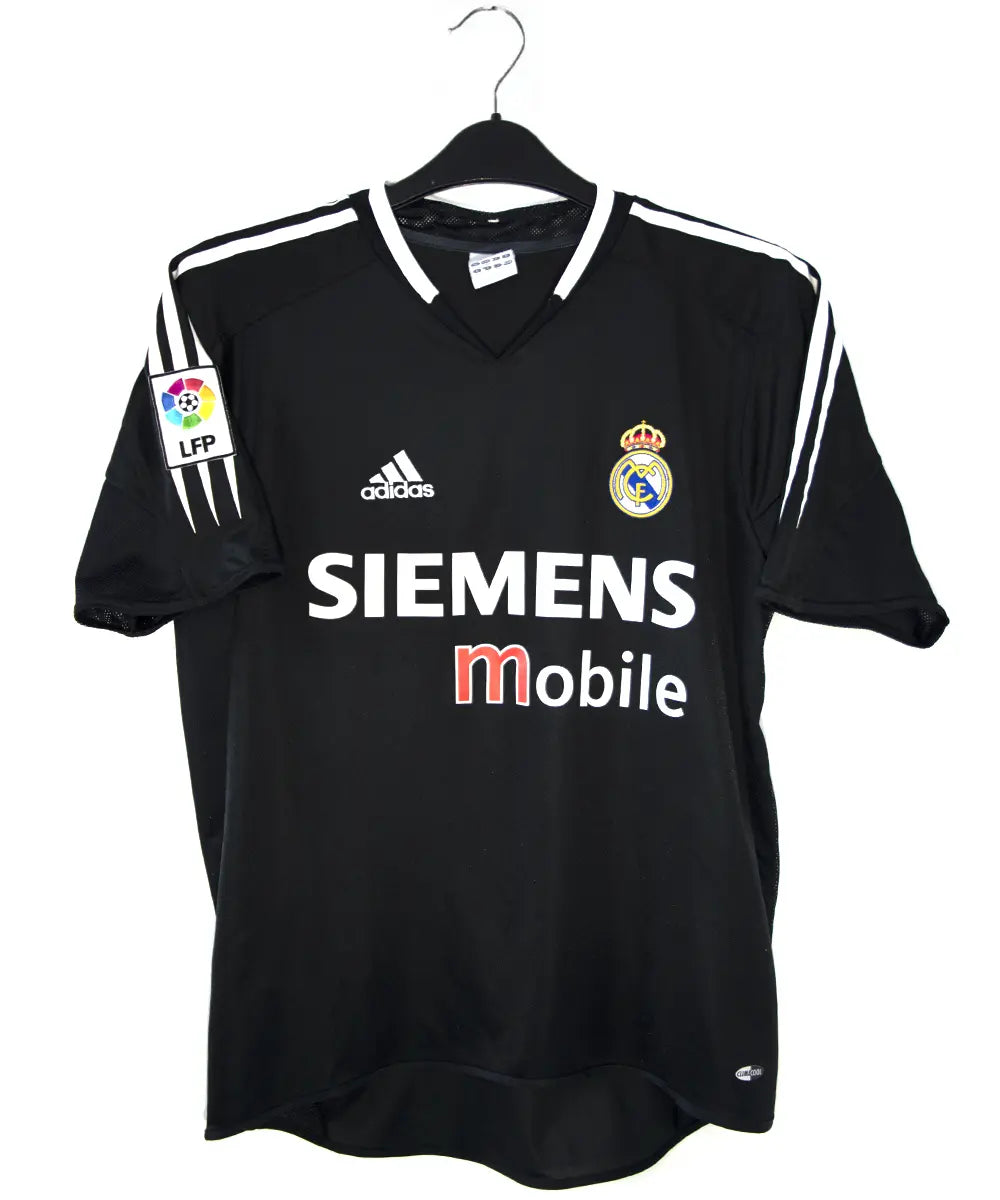 Maillot vintage extérieur noir et blanc du real madrid de la saison 2004-2005. On peut retrouver l'équipementier adidas et le sponsor siemens mobile. Le maillot est floqué du numéro 5 Zinedine Zidane