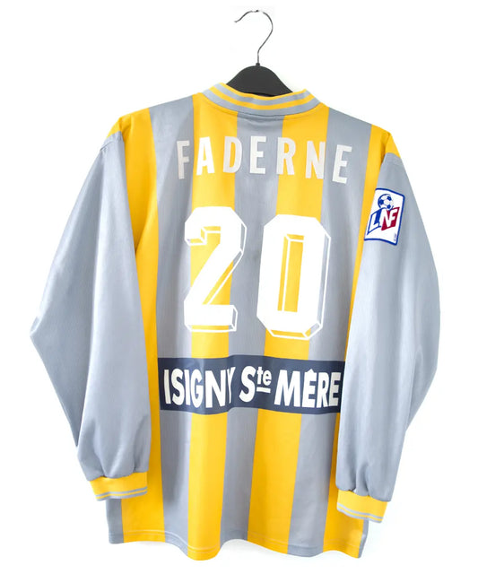 Maillot du SM Caen de la saison 2000-2001. Le maillot est de couleur gris et jaune. On peut retrouver l'équipementier le coq sportif, le sponsor infonie et le sponsor isigny sainte mère. On peut aussi retrouver l'ancien patch LNF. Le maillot est floqué du numéro 20 Faderne