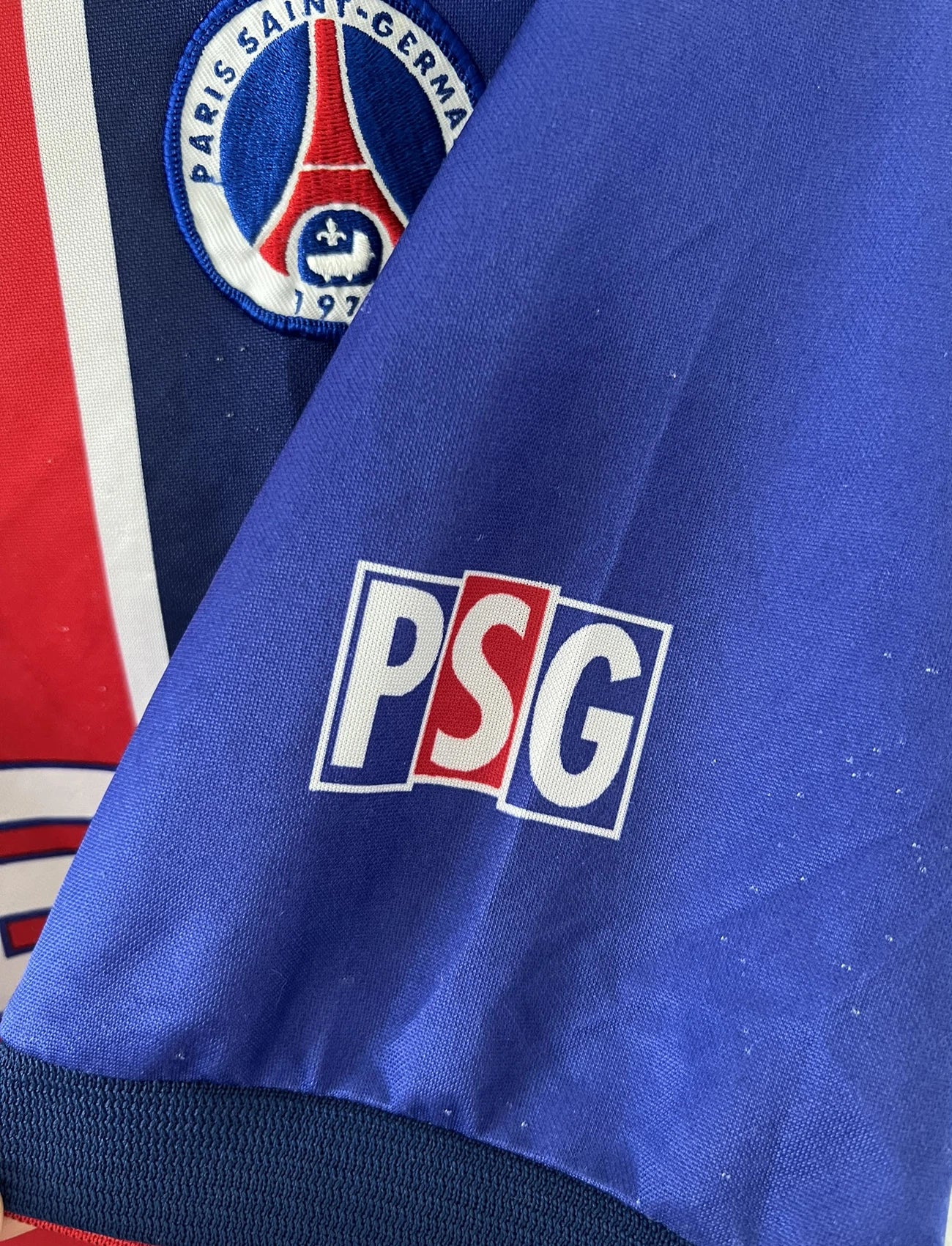 Maillot de foot vintage domicile du PSG de la saison 1998/1999. Le maillot est de couleur bleu blanc et rouge. On peut retrouver l'équipementier nike et le sponsor opel. Il s'agit d'un maillot authentique d'époque.