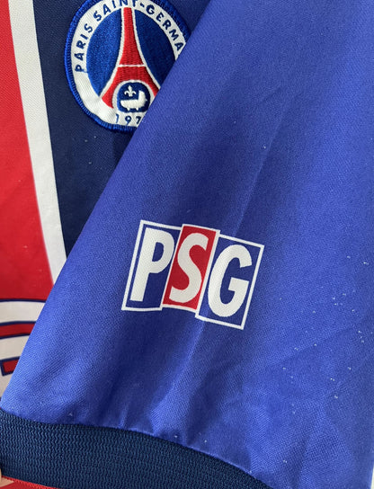 Maillot de foot vintage domicile du PSG de la saison 1998/1999. Le maillot est de couleur bleu blanc et rouge. On peut retrouver l'équipementier nike et le sponsor opel. Il s'agit d'un maillot authentique d'époque.