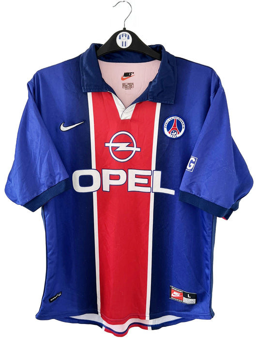 Maillot de foot vintage domicile du PSG de la saison 1998/1999. Le maillot est de couleur bleu blanc et rouge. On peut retrouver l'équipementier nike et le sponsor opel. Il s'agit d'un maillot authentique d'époque.