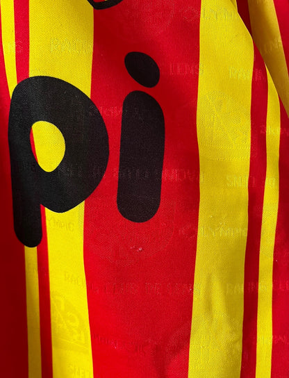 Maillot de foot vintage manches longues rouge et jaune du RC Lens 1994/1995. On peut retrouver l'équipementier Olympic et le sponsor Shopi. Il s'agit d'un maillot authentique d'époque.