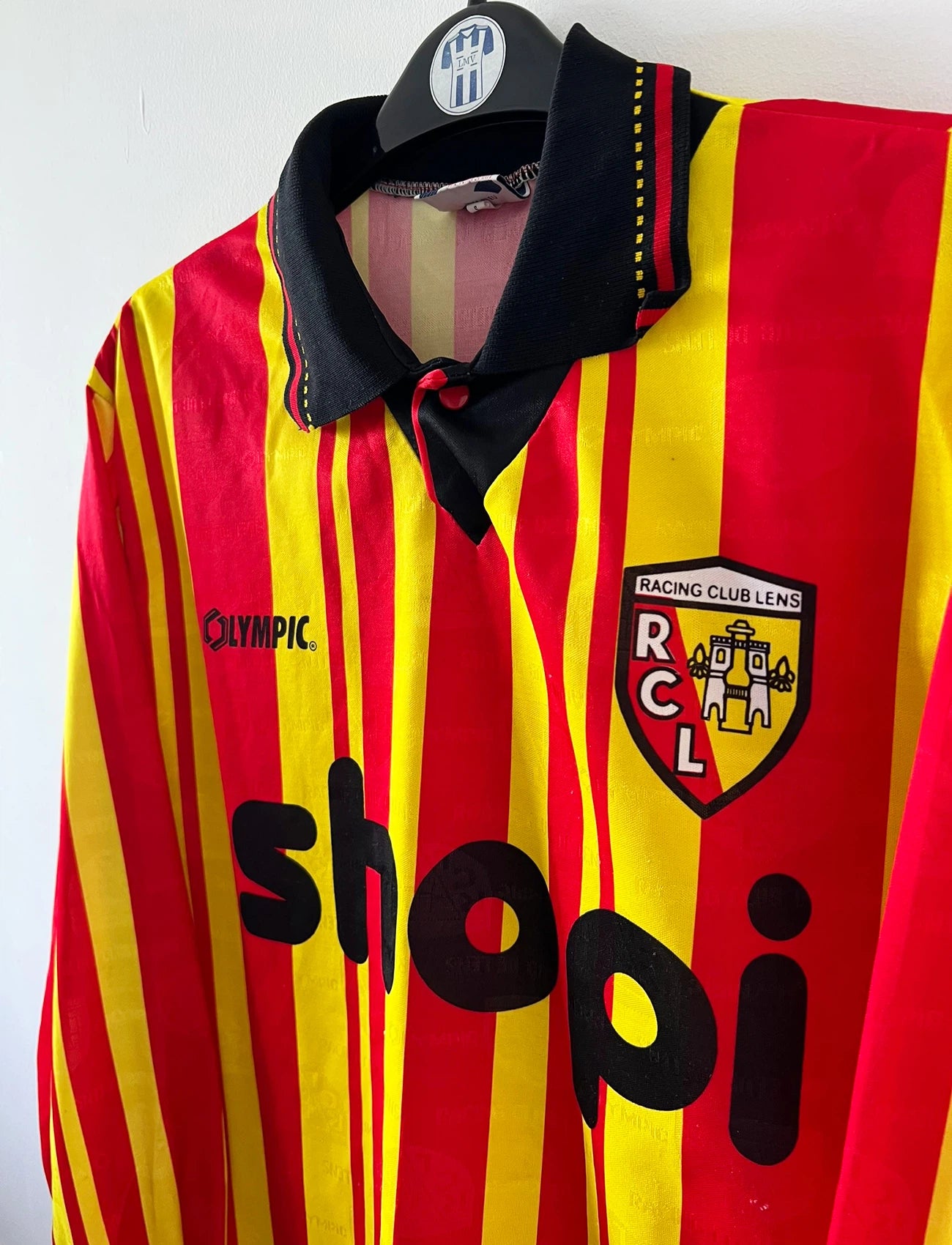 Maillot de foot vintage manches longues rouge et jaune du RC Lens 1994/1995. On peut retrouver l'équipementier Olympic et le sponsor Shopi. Il s'agit d'un maillot authentique d'époque.