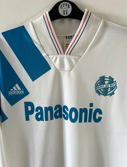 Maillot de foot vintage domicile blanc de l'OM 1992/1993. On peut retrouver l'équipementier Adidas et le sponsor Panasonic. Il s'agit d'un maillot authentique d'époque.