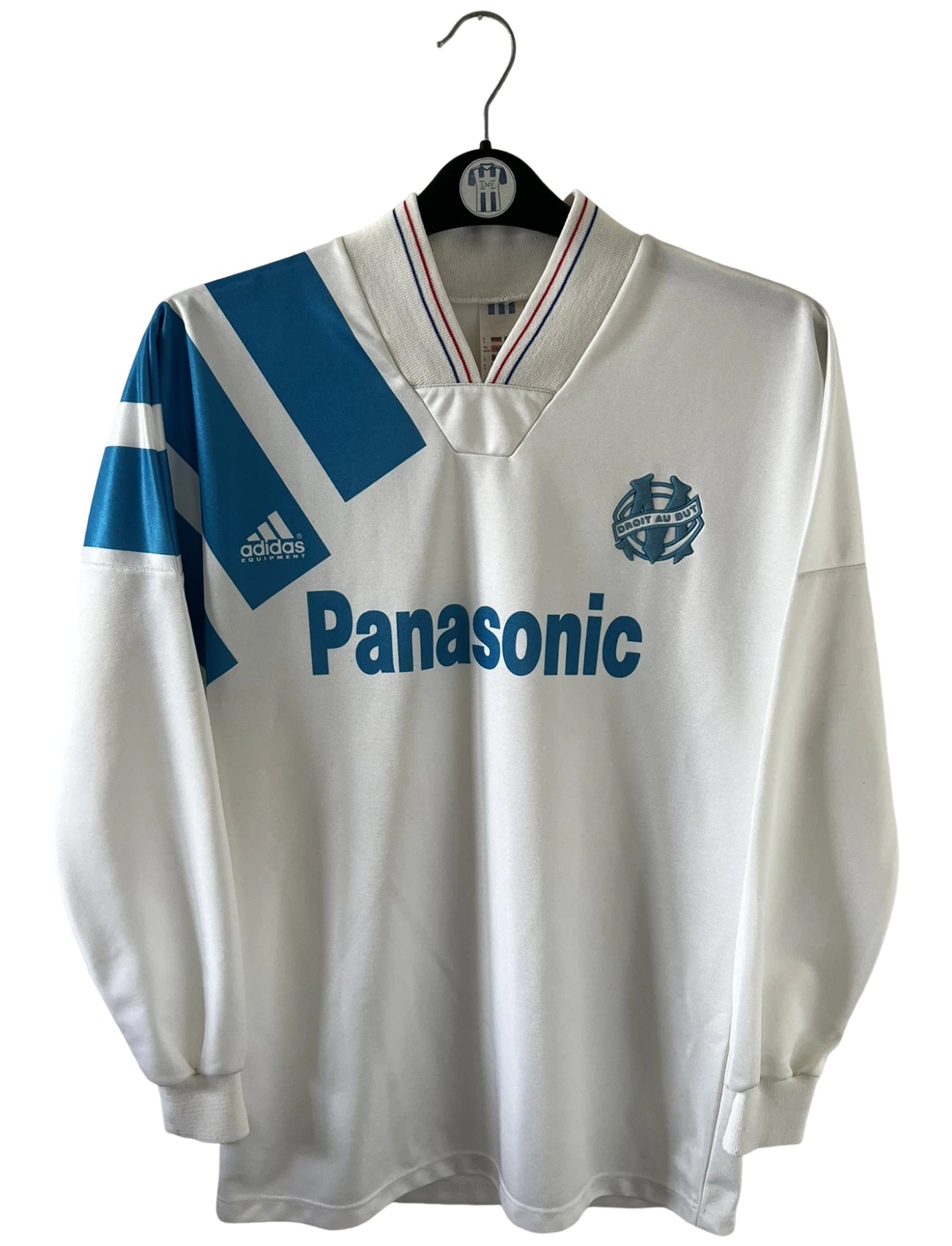 Maillot de foot vintage domicile blanc de l'OM 1992/1993. On peut retrouver l'équipementier Adidas et le sponsor Panasonic. Il s'agit d'un maillot authentique d'époque.