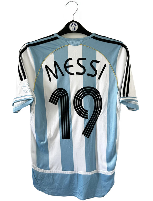 Maillot de foot vintage de l'argentine de la coupe du monde 2006. Le maillot est de couleur bleu et blanc. On peut retrouver l'équipementier adidas. Le maillot est floqué du numéro 19 Lionel Messi. Il s'agit d'un maillot authentique comportant les numéros 739802.