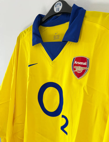 Maillot de foot vintage extérieur jaune d'arsenal de la saison 2003/2004. On peut retrouver l'équipementier Nike et le sponsor O2. Il s'agit d'un maillot authentique d'époque.