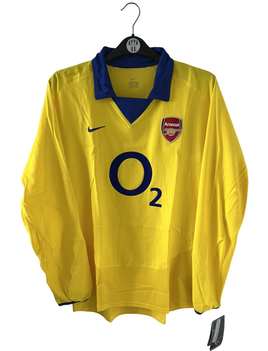 Maillot de foot vintage extérieur jaune d'arsenal de la saison 2003/2004. On peut retrouver l'équipementier Nike et le sponsor O2. Il s'agit d'un maillot authentique d'époque.
