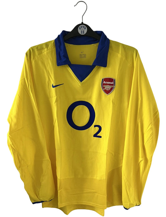 Maillot de foot vintage extérieur jaune d'arsenal de la saison 2003/2004. On peut retrouver l'équipementier Nike et le sponsor O2. Il s'agit d'un maillot authentique d'époque.