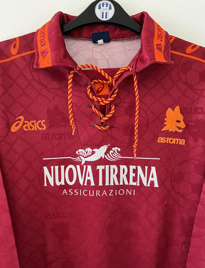 Maillot de foot vintage de l'AS Roma de la saison 1994/1995. Le maillot est de couleur rouge et orange. On peut retrouver l'équipementier asics et le sponsor nuova tirrena. Il s'agit d'un maillot authentique d'époque.