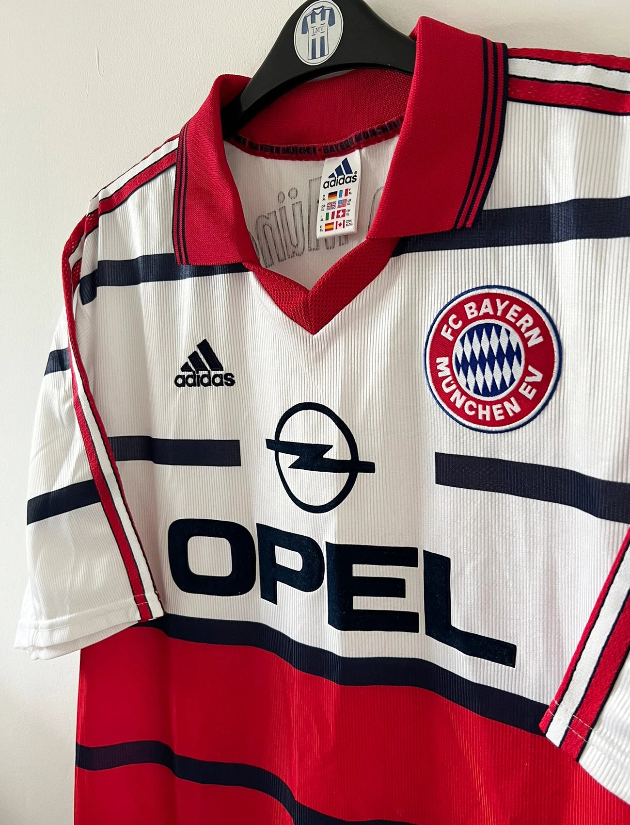 Maillot de foot vintage extérieur blanc et rouge du Bayern Munich 1998/2000. On peut retrouver l'équipementier Adidas et le sponsor Opel. Il s'agit d'un maillot authentique d'époque.