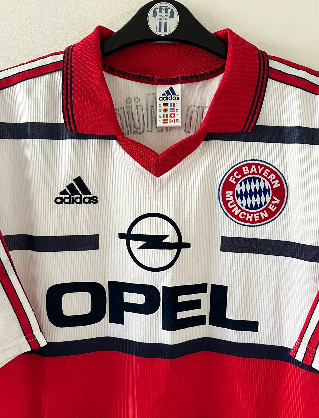 Maillot de foot vintage extérieur blanc et rouge du Bayern Munich 1998/2000. On peut retrouver l'équipementier Adidas et le sponsor Opel. Il s'agit d'un maillot authentique d'époque.