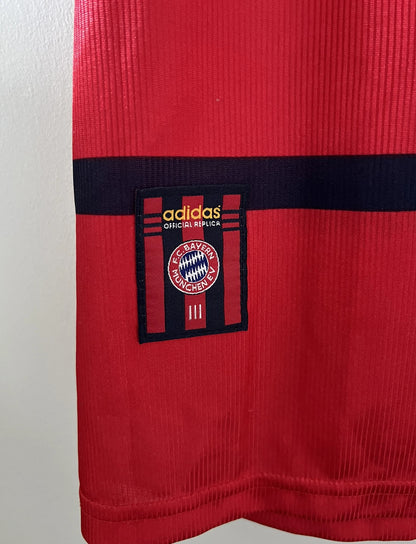 Maillot de foot vintage extérieur blanc et rouge du Bayern Munich 1998/2000. On peut retrouver l'équipementier Adidas et le sponsor Opel. Il s'agit d'un maillot authentique d'époque.