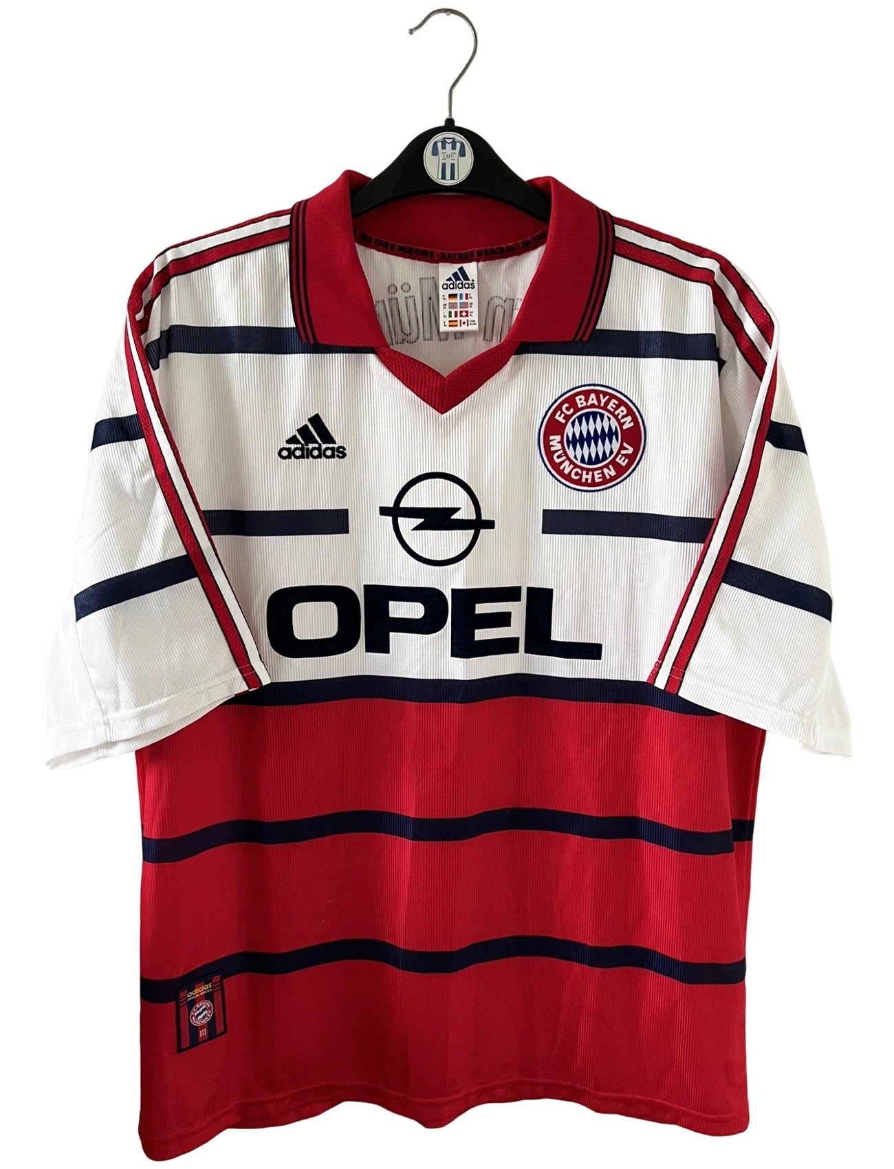 Maillot de foot vintage extérieur blanc et rouge du Bayern Munich 1998/2000. On peut retrouver l'équipementier Adidas et le sponsor Opel. Il s'agit d'un maillot authentique d'époque.