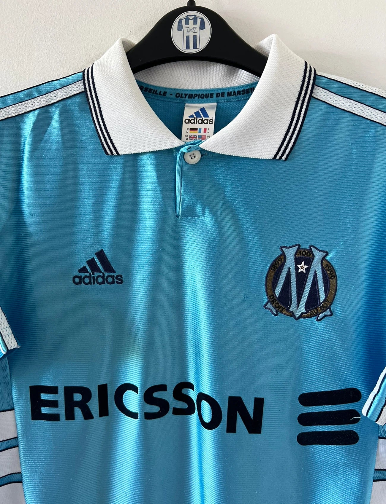 Maillot de foot vintage extérieur bleu de l'OM 1998/1999. On peut retrouver l'équipementier Adidas et le sponsor Ericsson. Il s'agit d'un maillot authentique d'époque.