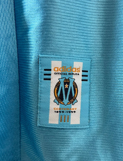 Maillot de foot vintage extérieur bleu de l'OM 1998/1999. On peut retrouver l'équipementier Adidas et le sponsor Ericsson. Il s'agit d'un maillot authentique d'époque.