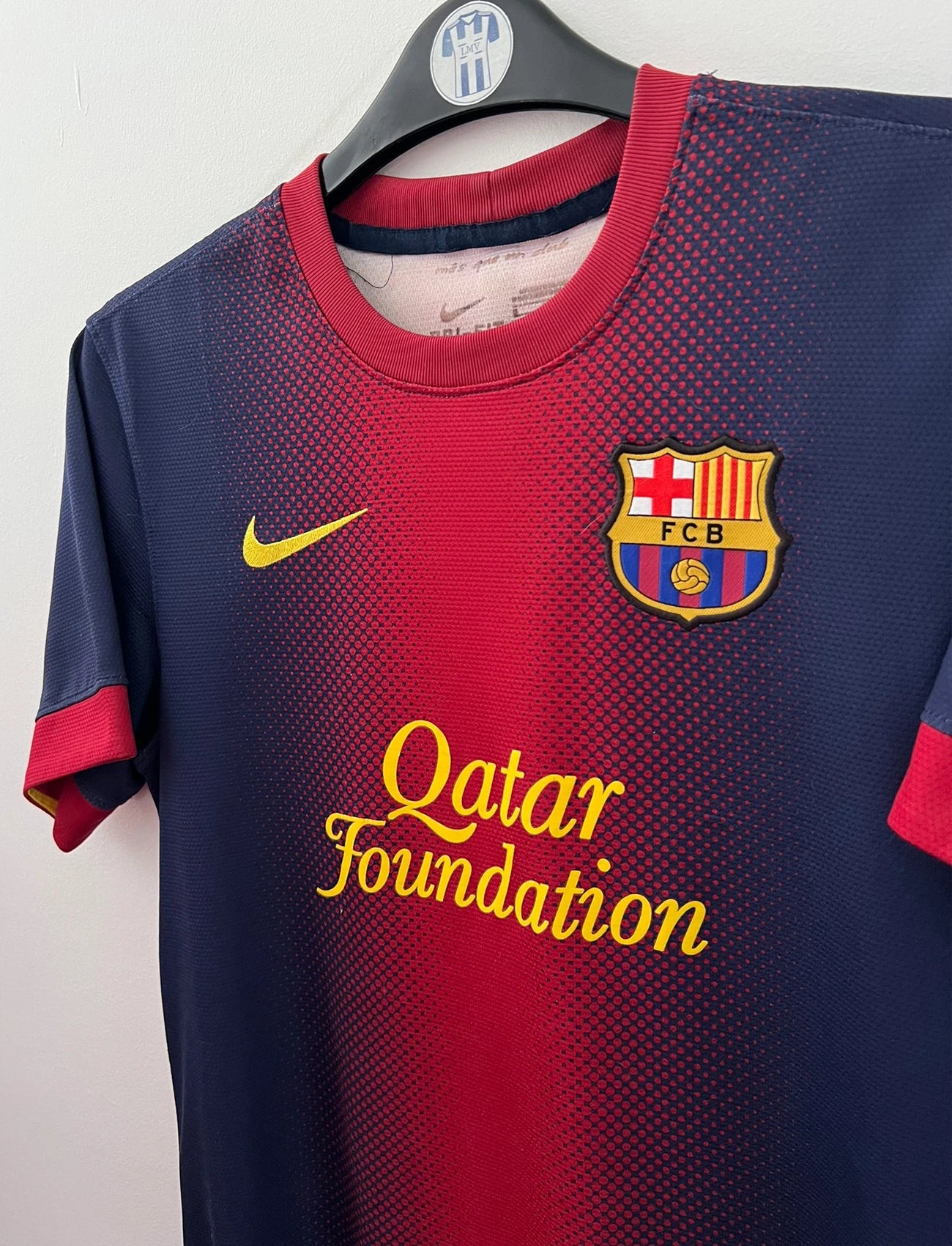 Maillot de foot vintage domicile rouge et bleu du FC Barcelone 2012/2013. On peut retrouver l'équipementier Nike et le sponsor Qatar Foundation. Le maillot est floqué du numéro 8 Andrés Iniesta. Il s'agit d'un maillot authentique d'époque.