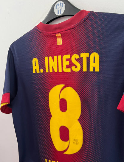 Maillot de foot vintage domicile rouge et bleu du FC Barcelone 2012/2013. On peut retrouver l'équipementier Nike et le sponsor Qatar Foundation. Le maillot est floqué du numéro 8 Andrés Iniesta. Il s'agit d'un maillot authentique d'époque.