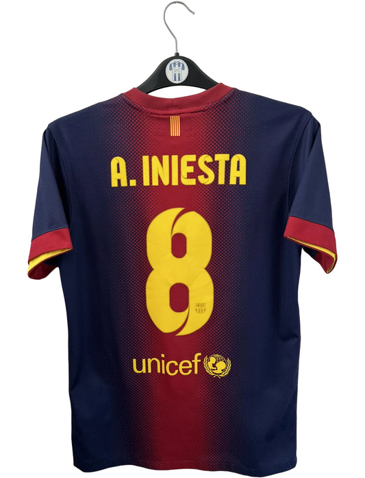 Maillot de foot vintage domicile rouge et bleu du FC Barcelone 2012/2013. On peut retrouver l'équipementier Nike et le sponsor Qatar Foundation. Le maillot est floqué du numéro 8 Andrés Iniesta. Il s'agit d'un maillot authentique d'époque.
