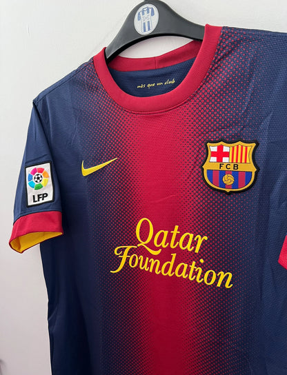Maillot de foot vintage domicile rouge et bleu du FC Barcelone 2012/2013. On peut retrouver l'équipementier Nike et le sponsor Qatar Foundation. Le maillot est floqué du numéro 10 Lionel Messi. Il s'agit d'un maillot authentique d'époque.