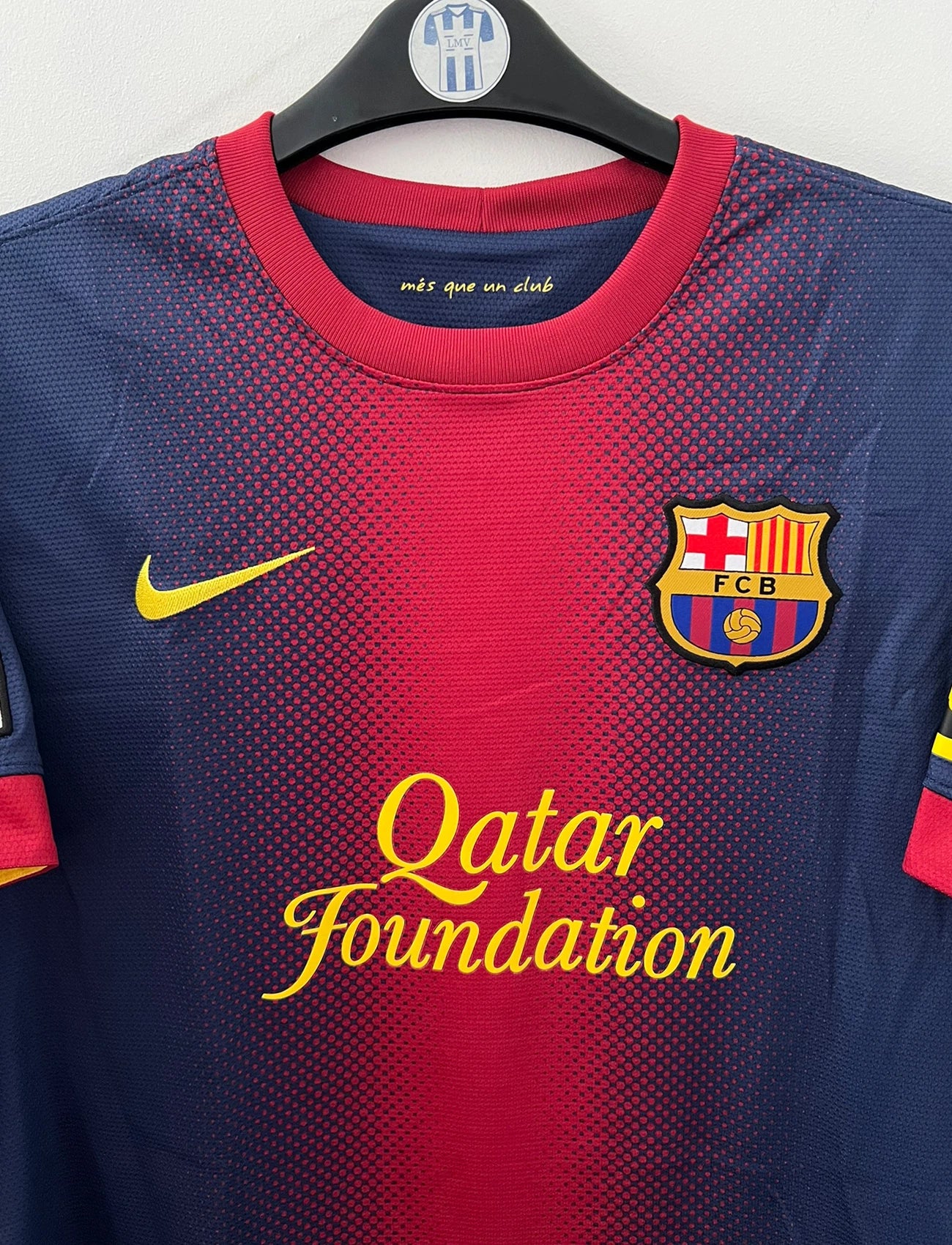 Maillot de foot vintage domicile rouge et bleu du FC Barcelone 2012/2013. On peut retrouver l'équipementier Nike et le sponsor Qatar Foundation. Le maillot est floqué du numéro 10 Lionel Messi. Il s'agit d'un maillot authentique d'époque.