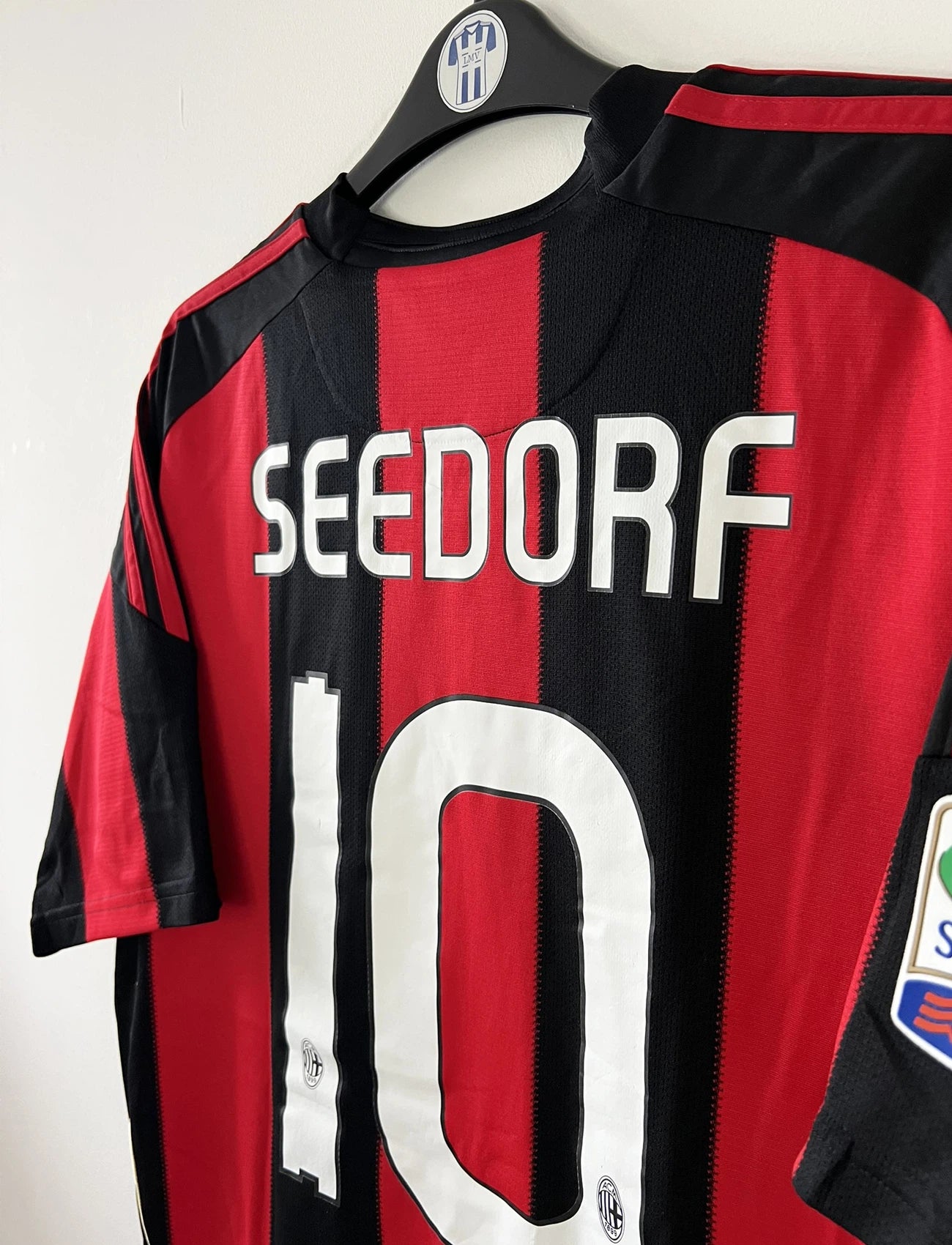 Maillot de foot vintage domicile de l'AC Milan de la saison 2010/2011. On peut retrouver l'équipementier Adidas et le sponsor Fly Emirates. Le maillot est floqué du numéro 10 Clarence Seedorf. Il s'agit d'un maillot authentique d'époque comportant les numéros P96288