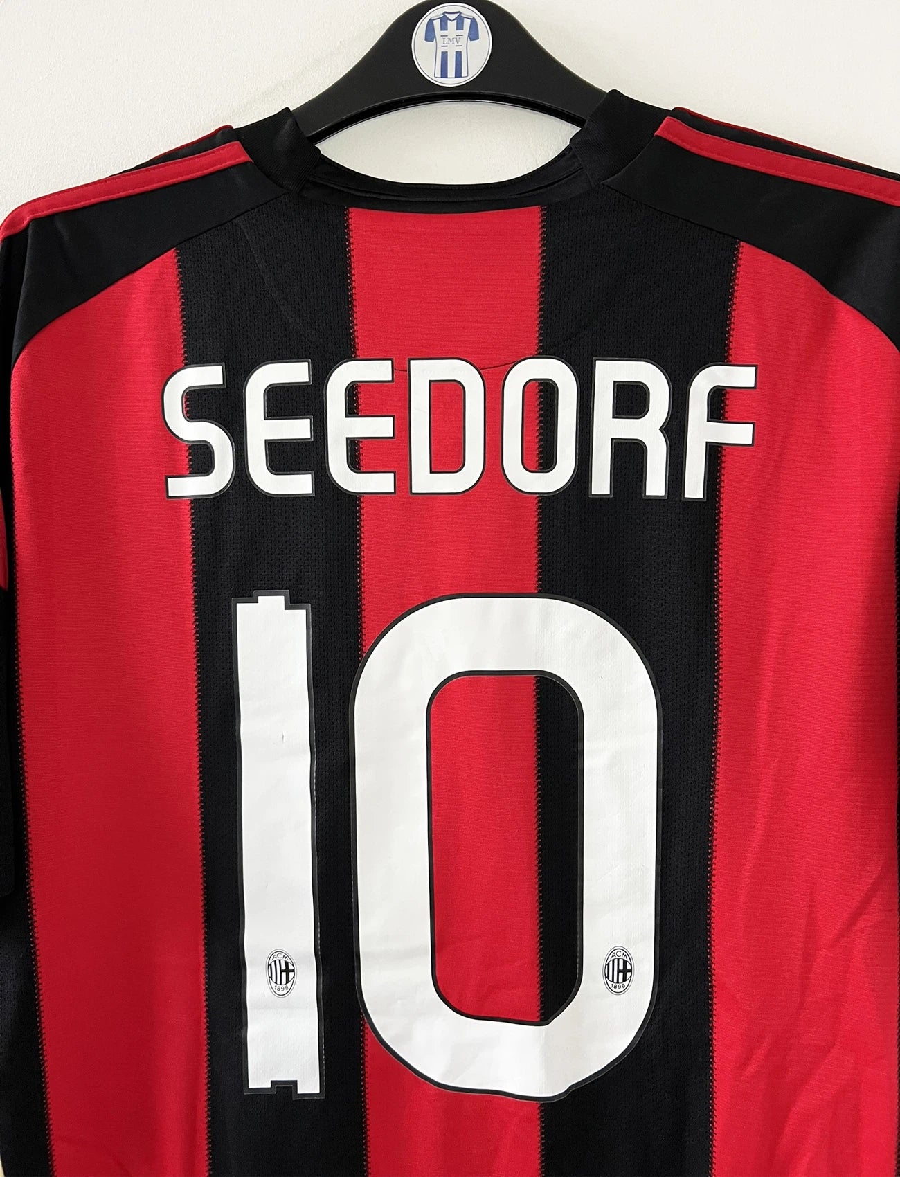 Maillot de foot vintage domicile de l'AC Milan de la saison 2010/2011. On peut retrouver l'équipementier Adidas et le sponsor Fly Emirates. Le maillot est floqué du numéro 10 Clarence Seedorf. Il s'agit d'un maillot authentique d'époque comportant les numéros P96288