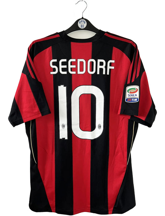 Maillot de foot vintage domicile de l'AC Milan de la saison 2010/2011. On peut retrouver l'équipementier Adidas et le sponsor Fly Emirates. Le maillot est floqué du numéro 10 Clarence Seedorf. Il s'agit d'un maillot authentique d'époque comportant les numéros P96288