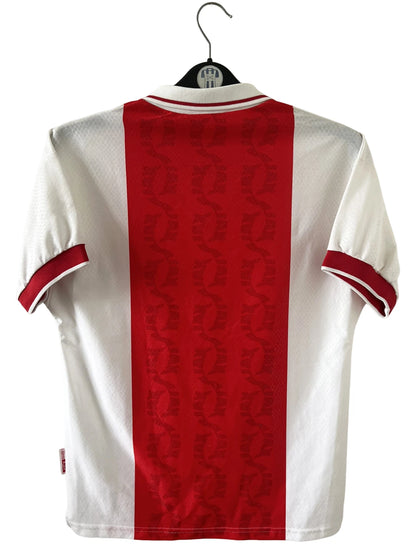 Maillot de foot vintage domicile rouge et blanc de l'Ajax Amsterdam de la saison 1998/1999. On peut retrouver l'équipementier Umbro et le sponsor ABN AMRO. Il s'agit d'un maillot authentique d'époque.